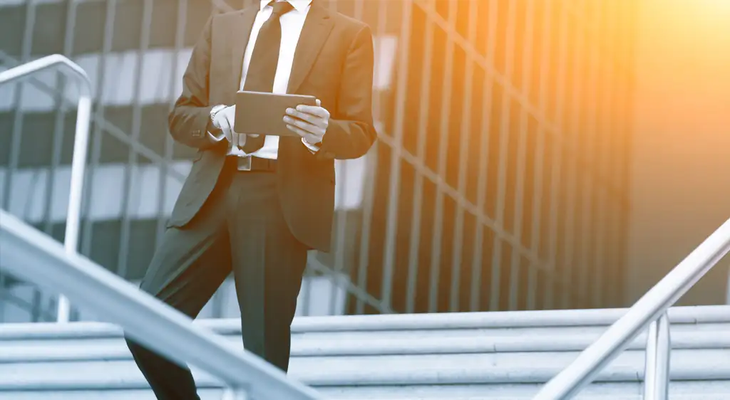 Novedades fiscales para autónomos imagen de un profesional revisando información en una tablet frente a un edificio corporativo