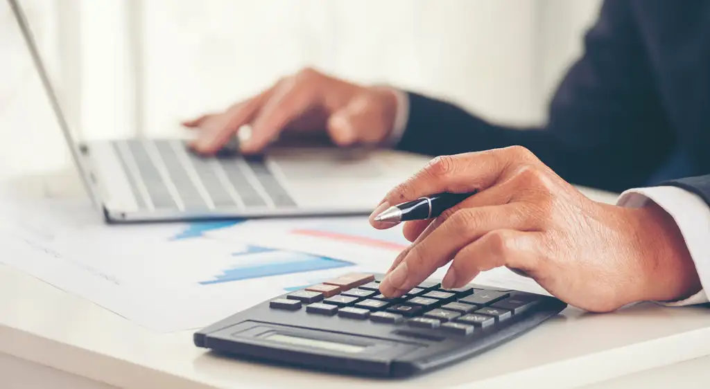Manos calculando y gestionando datos en oficina, ideal para servicios de consultoría fiscal Madrid y gestión empresarial.