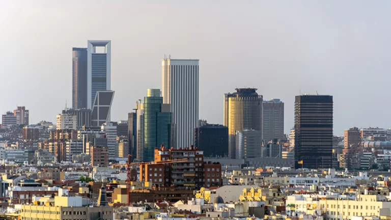 Panorama urbano con modernos rascacielos al atardecer, presion fiscal madrid destaca en un horizonte lleno de edificios.