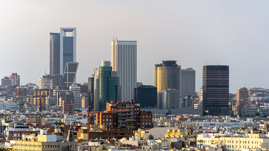 Panorama urbano con modernos rascacielos al atardecer, presion fiscal madrid destaca en un horizonte lleno de edificios.